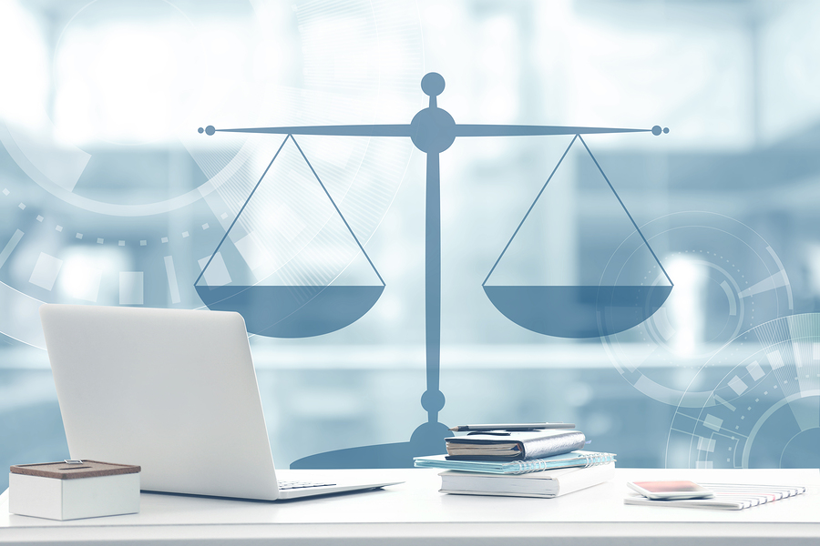 Law concept. Lawyer workplace with laptop and scales of justice design on blurred background.